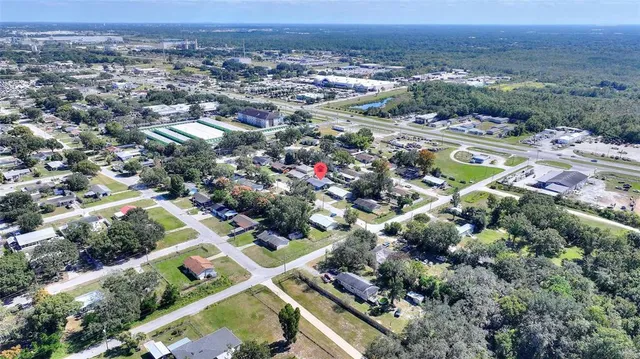 an aerial view of a residential houses with outdoor space and trees