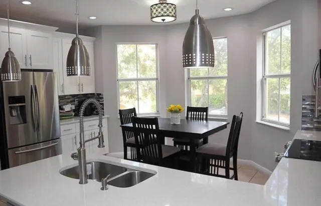 a kitchen with stainless steel appliances a dining table chairs and window