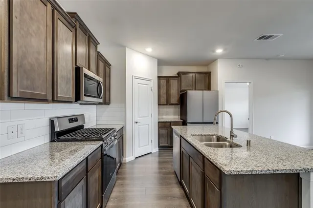 a kitchen with stainless steel appliances granite countertop a sink stove and refrigerator