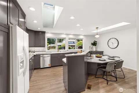a kitchen with stainless steel appliances kitchen island granite countertop a sink cabinets and wooden floor