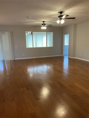 a view of an empty room with window and wooden floor