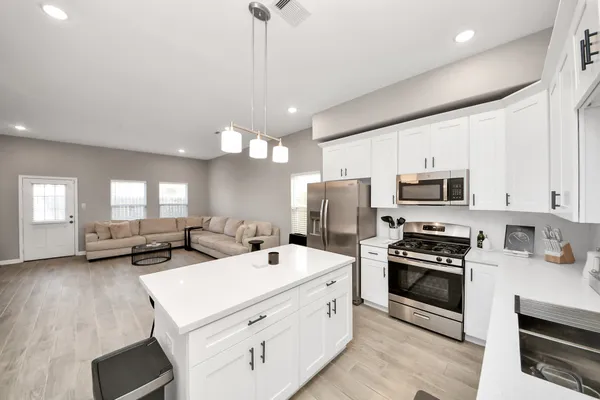 a kitchen with stainless steel appliances a table chairs refrigerator and sink
