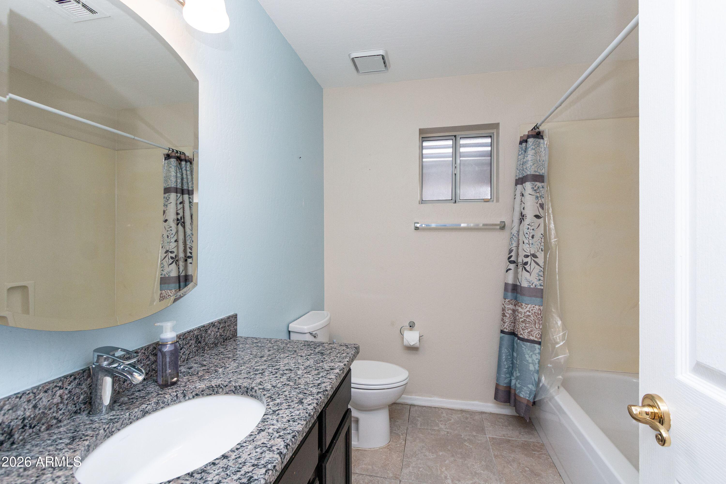 450 East Merrill Avenue Gilbert, AZ 85234 - Photo 24 of 26 a bathroom with a granite countertop sink toilet a mirror and shower