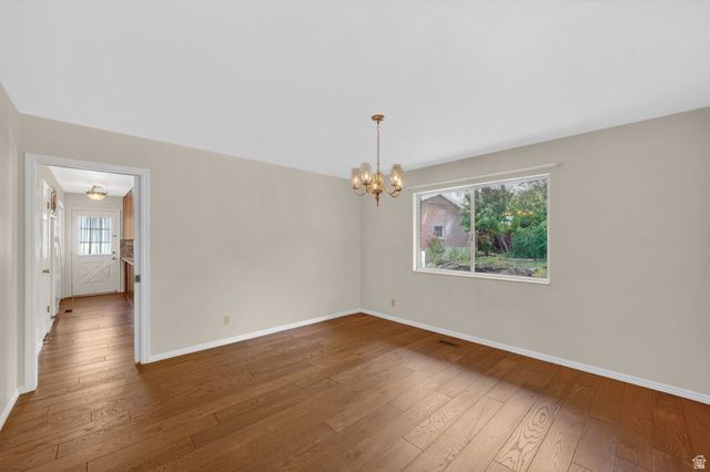 3120 North Apache Way Provo, UT 84604 - Photo 27 of 58 Spacious room featuring wood-finish flooring, a multi-pane window, and a brass chandelier