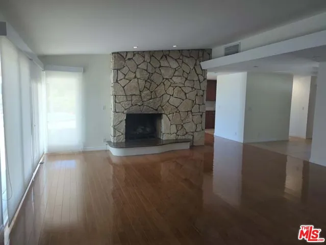 a view of empty room with wooden floor and fireplace