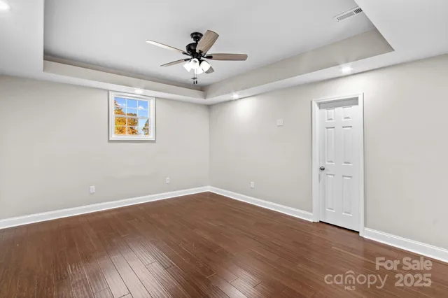 an empty room with wooden floor and ceiling fan