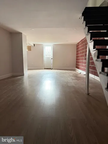 a view of an empty room with wooden floor and windows