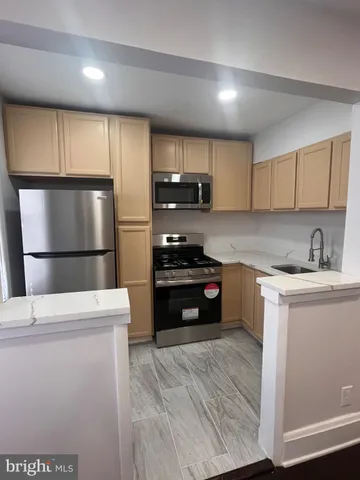 a kitchen with granite countertop a refrigerator and a stove top oven