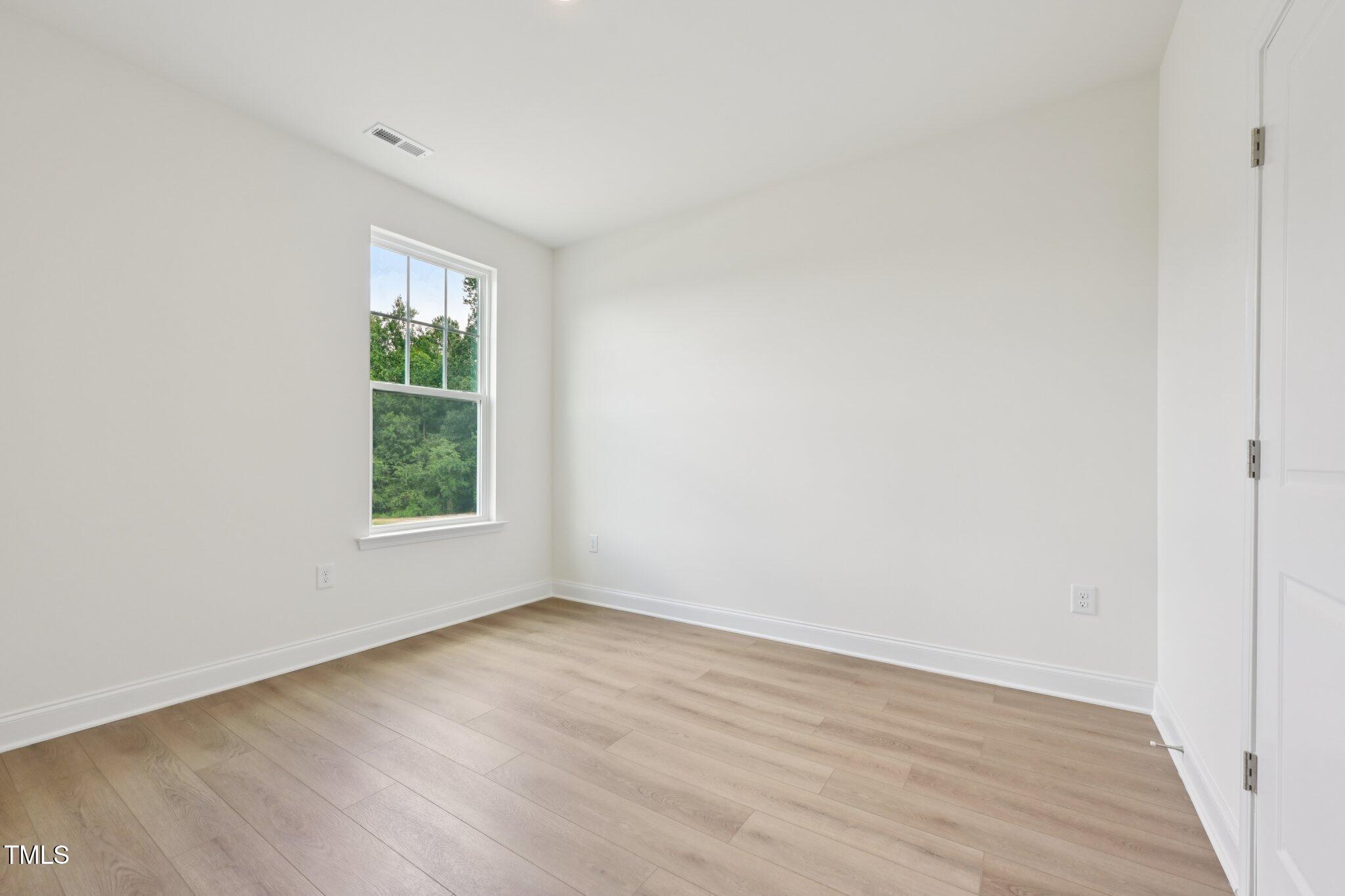 214 Alden Way Angier, NC 27501 - Photo 14 of 35 an empty room with wooden floor and windows