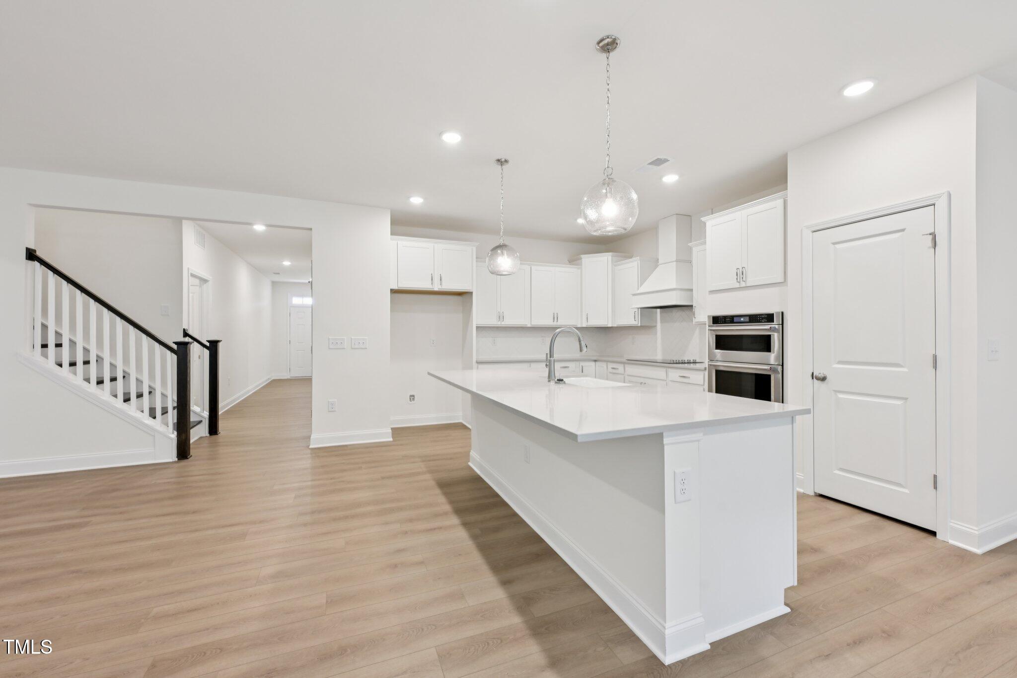 214 Alden Way Angier, NC 27501 - Photo 7 of 35 a large white kitchen with kitchen island a sink a center island stainless steel appliances and a cabinets