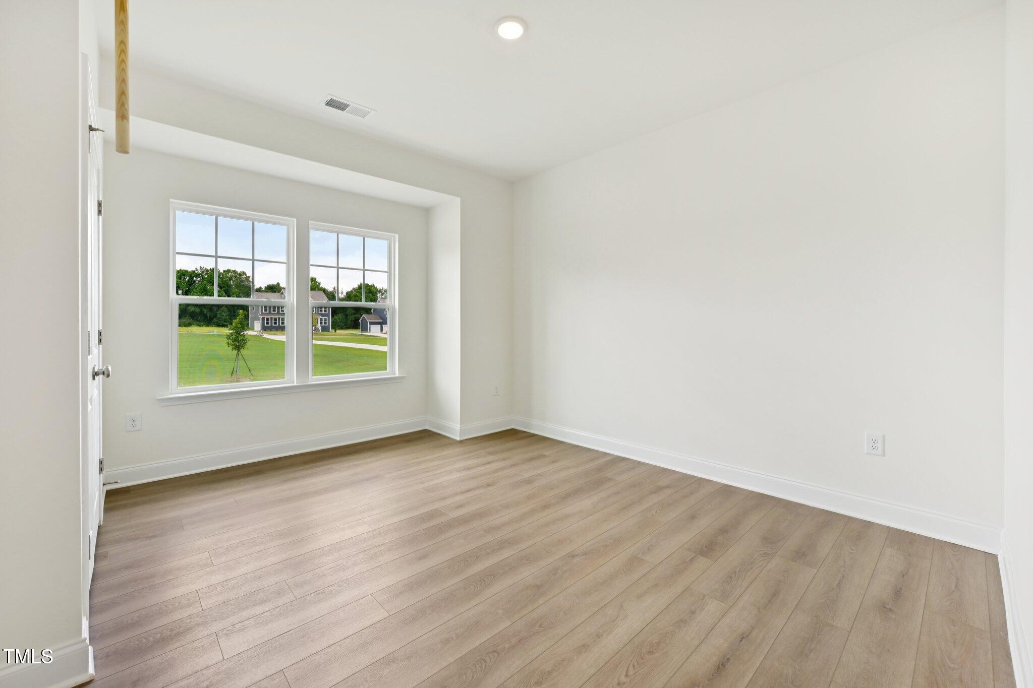 214 Alden Way Angier, NC 27501 - Photo 10 of 35 an empty room with wooden floor and windows