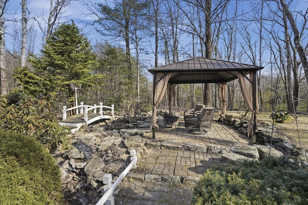 4 Charnock Circle Rutland, MA 01543 - Photo 37 of 42 a view of a patio with table and chairs under an umbrella with large trees