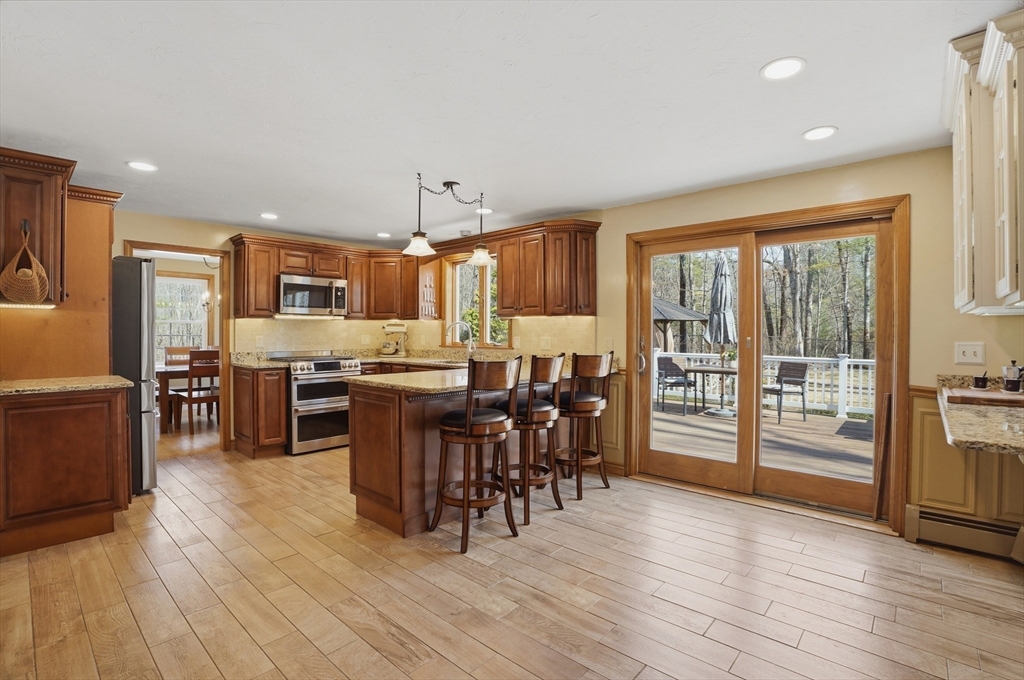 4 Charnock Circle Rutland, MA 01543 - Photo 5 of 42 a kitchen with stainless steel appliances kitchen island granite countertop a stove top oven a sink dishwasher a dining table and chairs with wooden floor