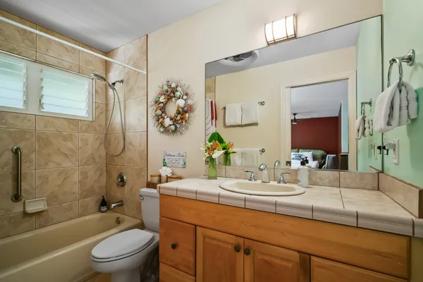 a bathroom with a granite countertop sink a toilet and shower