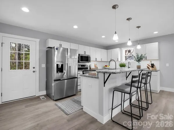 a kitchen with stainless steel appliances a refrigerator a stove a sink dishwasher and a refrigerator with wooden floor