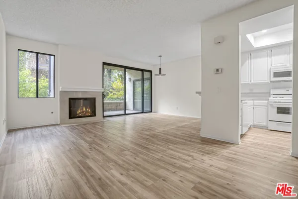 an empty room with wooden floor fireplace and windows