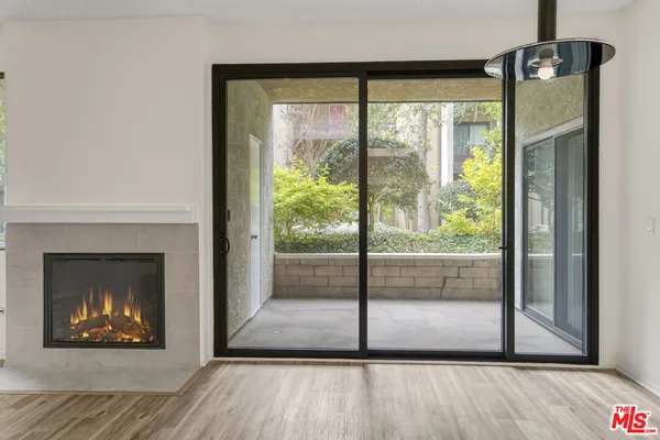 a view of an empty room with wooden floor and a fireplace