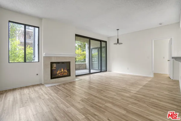 a view of an empty room with a window and fireplace