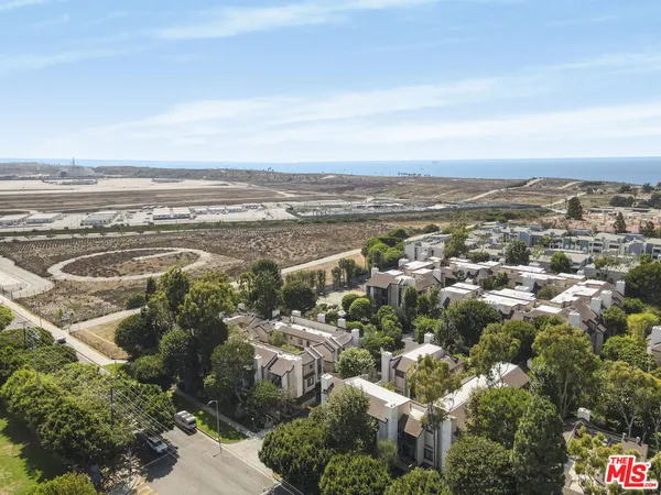 an aerial view of ocean and residential houses with outdoor space