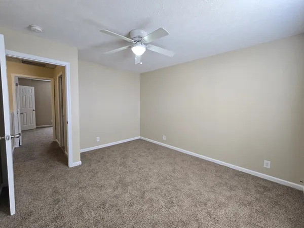 an empty room with a fan & a window