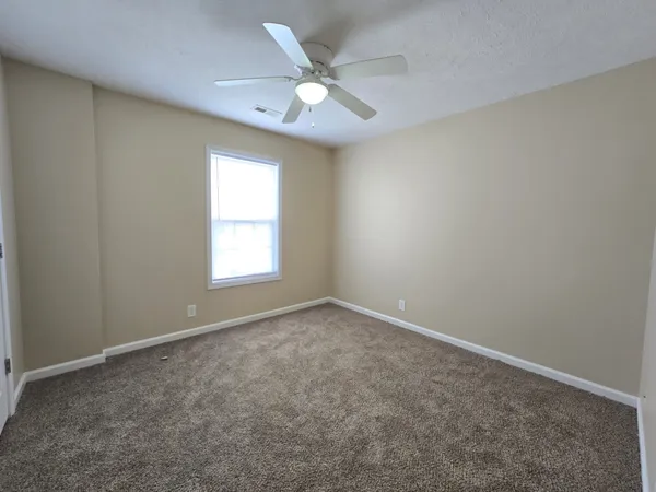 an empty room with windows and ceiling fan