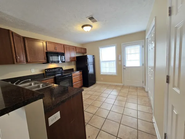 a kitchen with granite countertop a stove a sink and a refrigerator