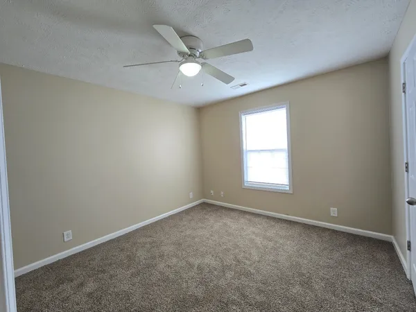 an empty room with a window and a fan