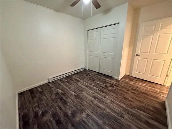 a view of an empty room with window and chandelier fan