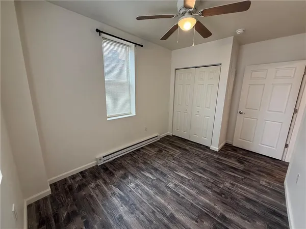 a view of an empty room with wooden floor and a ceiling fan