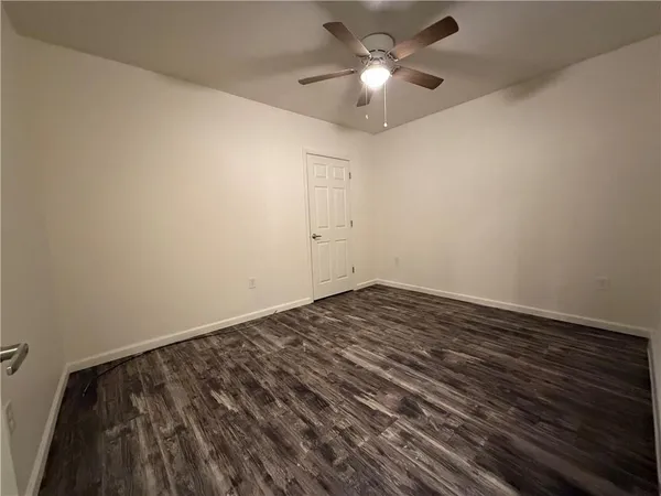 an empty room with a ceiling fan and wooden floor