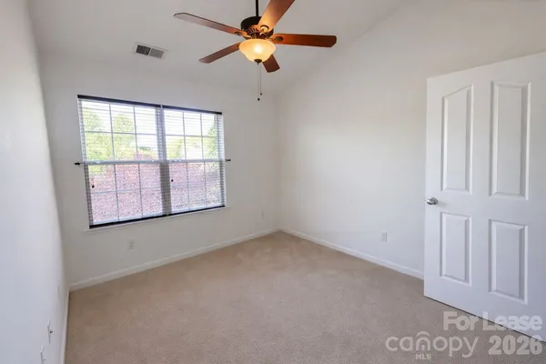 an empty room with windows and fan
