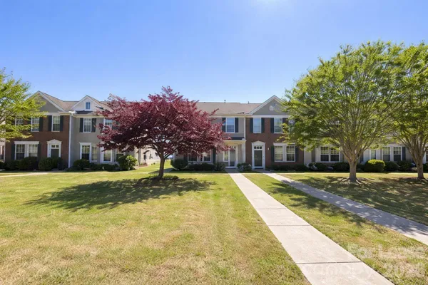 a view of yellow house with a yard and large trees