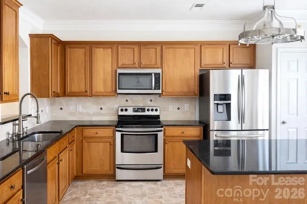 a kitchen with granite countertop a refrigerator stove and microwave
