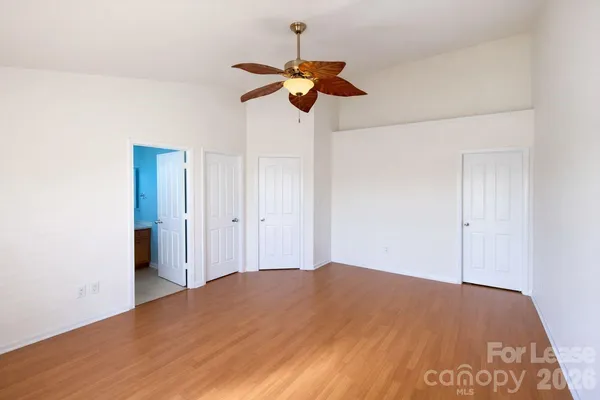 a view of a room with a chandelier fan and wooden floor