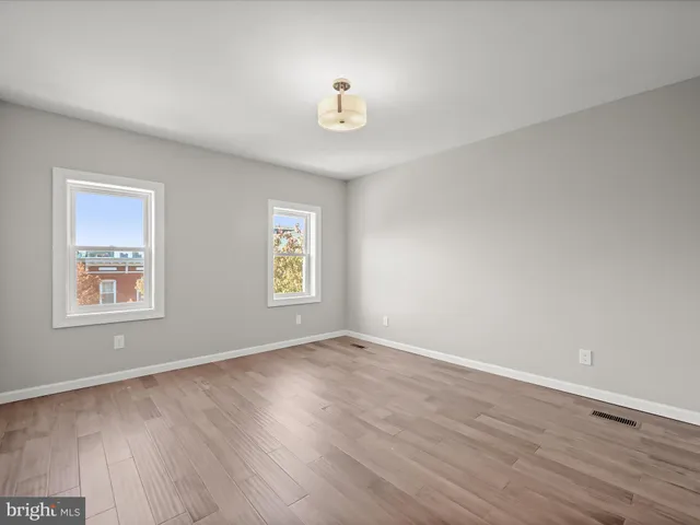 a view of an empty room with window and wooden floor