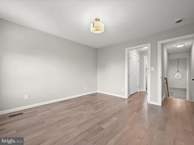 a view of an empty room with wooden floor and a chandelier