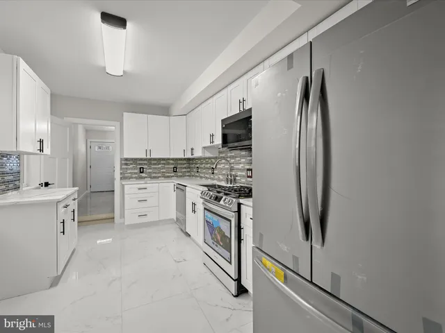 a kitchen with stainless steel appliances a refrigerator sink and white cabinets