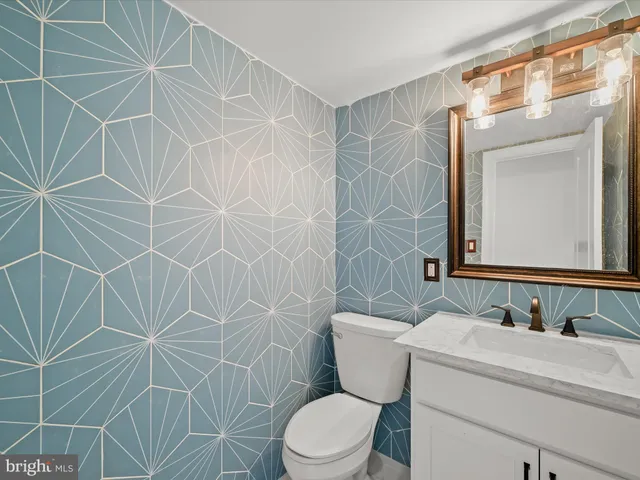 a bathroom with a toilet sink vanity and mirror