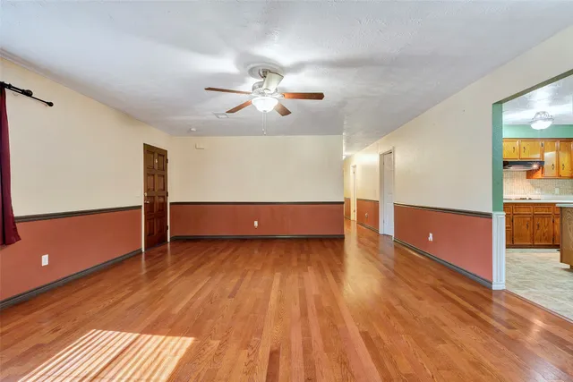 a view of a room with wooden floor and ceiling fan