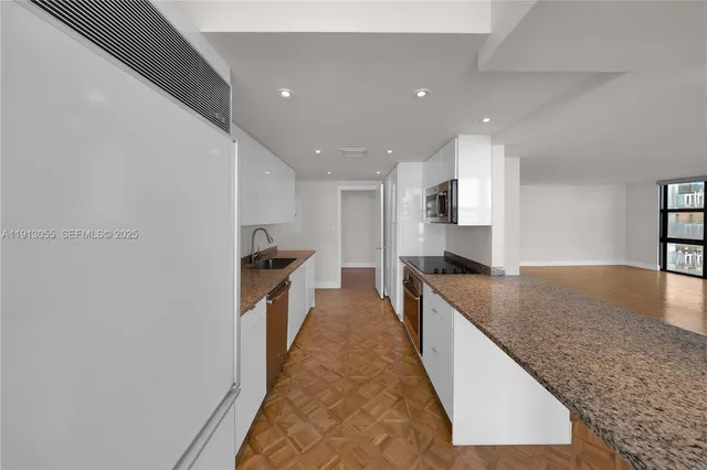 a large kitchen with stainless steel appliances granite countertop a sink and a refrigerator