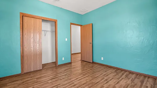 an empty room with wooden floor and closet