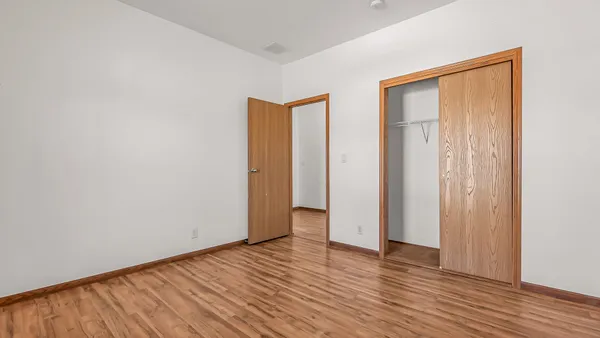 a view of an empty room with wooden floor and closet