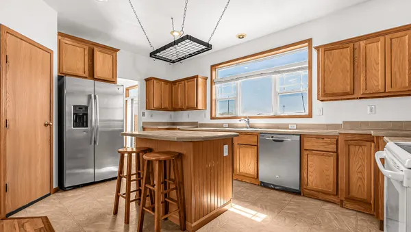 a kitchen with granite countertop a sink cabinets stainless steel appliances and a window