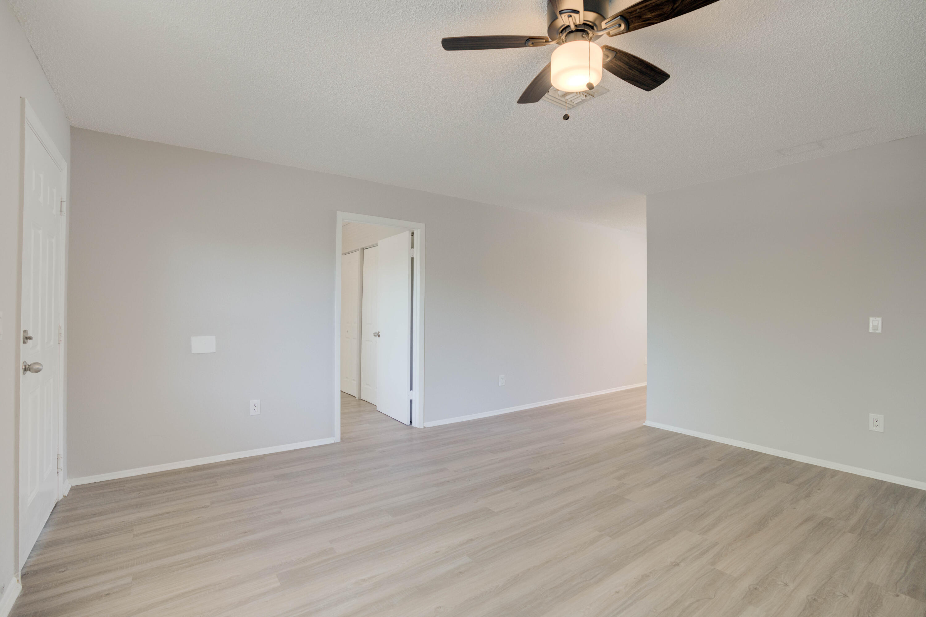 6610 Jupiter Gardens Boulevard, Unit F Jupiter, FL 33458 - Photo 11 of 14 a view of an empty room with wooden floor and a ceiling fan
