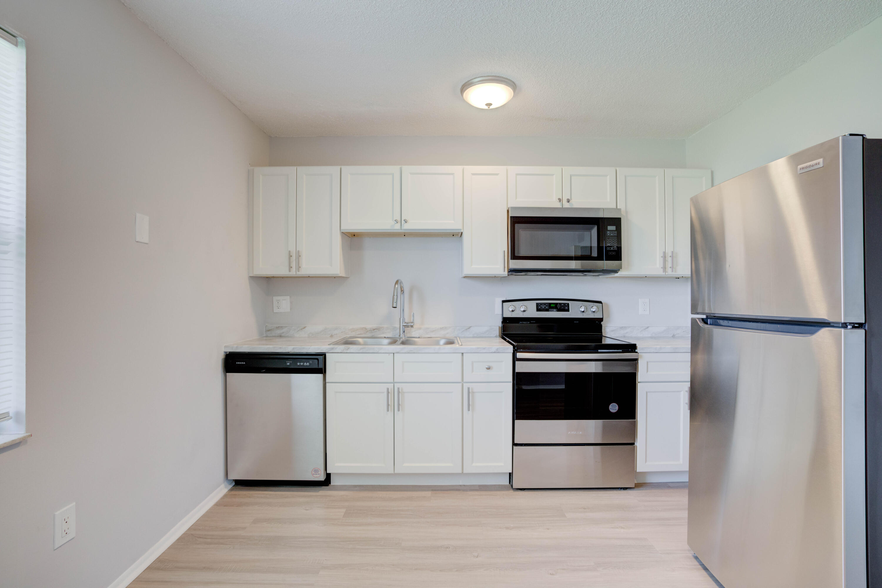 6610 Jupiter Gardens Boulevard, Unit F Jupiter, FL 33458 - Photo 6 of 14 a kitchen with stainless steel appliances a stove a microwave and a refrigerator