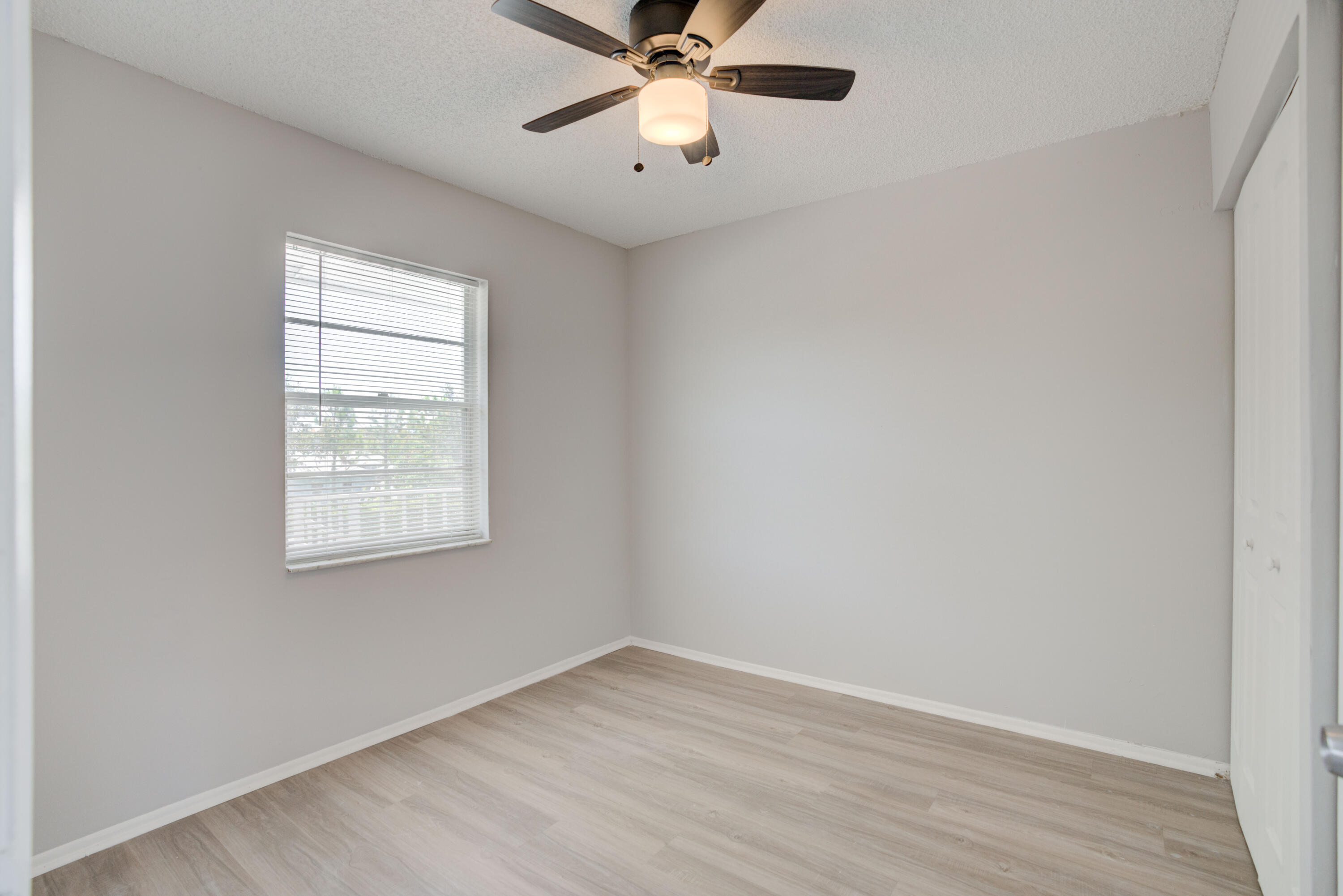 6610 Jupiter Gardens Boulevard, Unit F Jupiter, FL 33458 - Photo 7 of 14 an empty room with a window and a fan