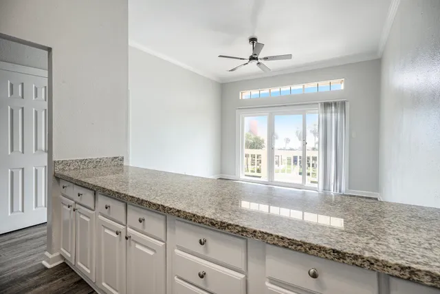 a hallway with granite countertop a sink and white cabinets