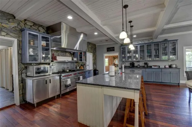 a kitchen with stainless steel appliances granite countertop a sink a stove and a wooden floors