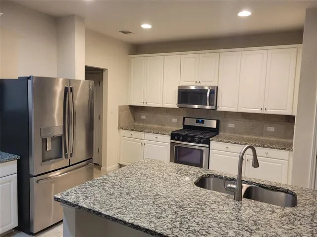 a kitchen with granite countertop a refrigerator stove and sink