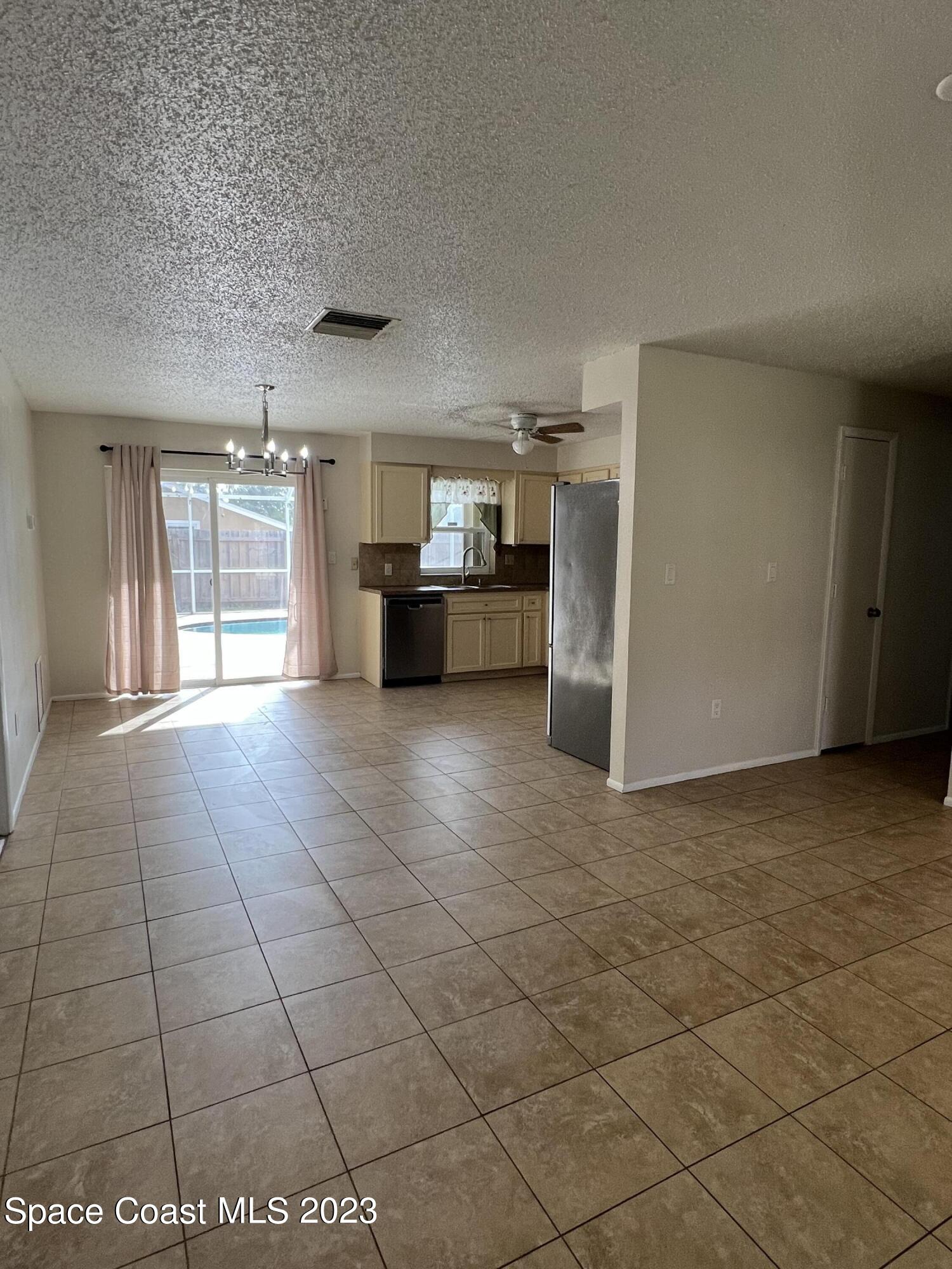 283 Fecco Street Cocoa, FL 32927 - Photo 4 of 25 a view of a refrigerator in kitchen and an empty room